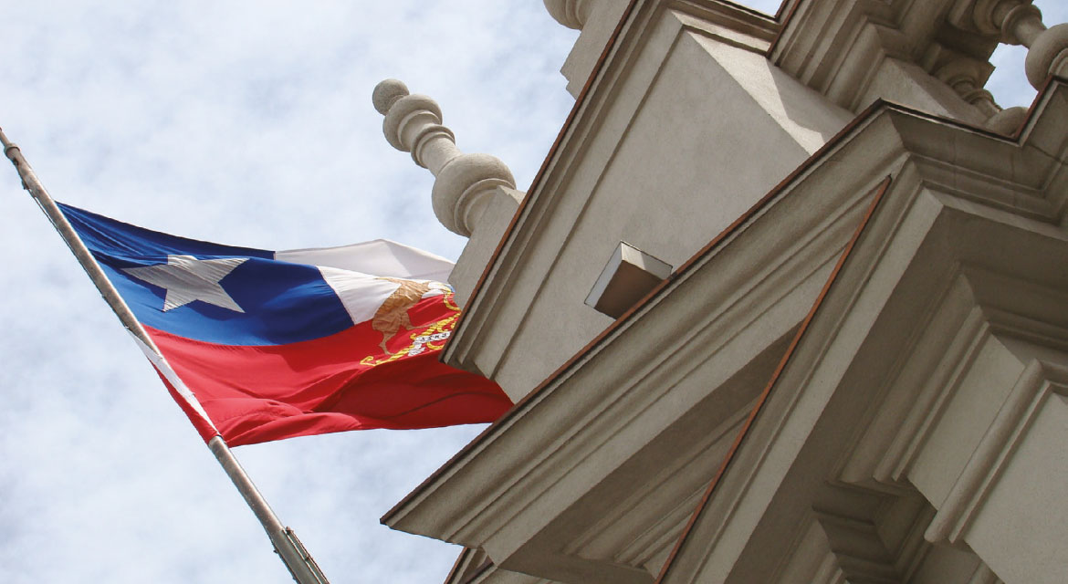 Imagen de la bandera de Chile sobre edificio institucional