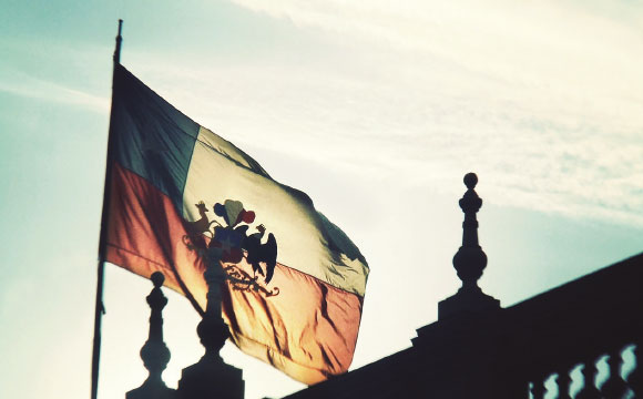 Imagen de la bandera de Chile sobre edificio institucional